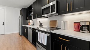 A modern kitchen with black cabinets, stainless steel appliances, and a white countertop.