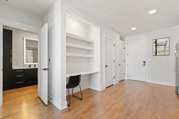 A spacious room with a built-in closet, a black chair, and a refrigerator. - Beautiful Modern 1BD | Walk to Raymond James! (Tampa)