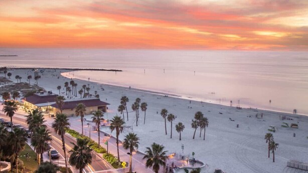 A beach with palm trees and a building in the foreground.