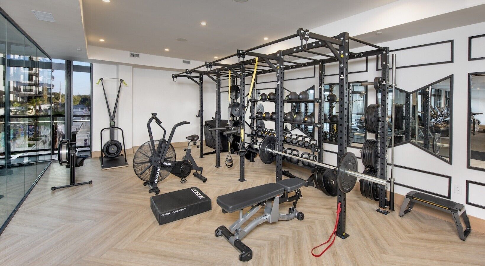 A modern gym with exercise equipment, a rowing machine, and a bench.