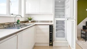 A compact kitchen with white cabinets, a built-in dishwasher, and a window providing natural light.