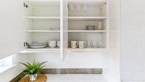 A white kitchen with open shelves displaying plates, bowls, and cups.