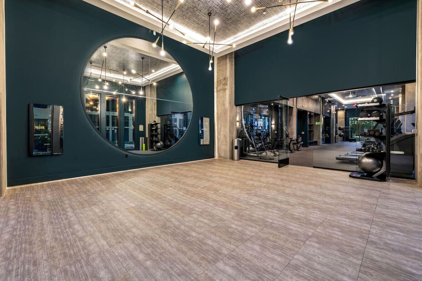A gym with a large mirror, exercise equipment, and a wooden floor.