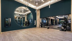 Une salle de sport dotée d’un grand miroir, d’appareils d’exercice et d’un plancher en bois.