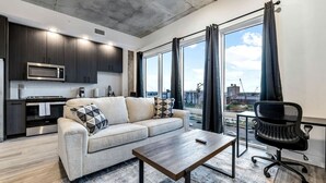 Un appartement moderne doté d’une kitchenette, d’un canapé, d’une table basse et offrant une vue sur la ville.