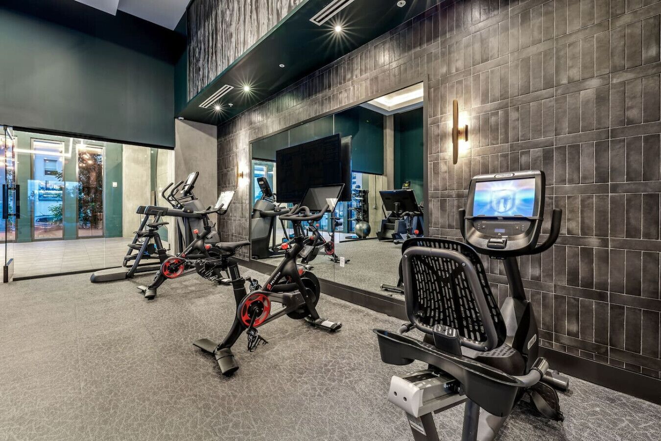 Une salle de sport moderne équipée de vélos d’appartement, d’un rameur et d’un écran de télévision.