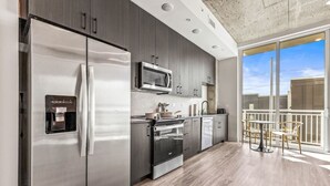 Una cocina moderna con electrodomésticos de acero inoxidable, un dispensador de agua y vistas a un balcón.