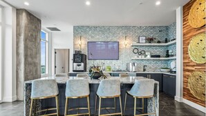 Una cocina moderna con una isla central, taburetes de bar y un salpicadero con estampado de espiga.