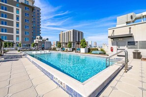 A swimming pool with a 4 ft. 8 in. depth marker, surrounded by a tiled deck and adjacent to a building with multiple floors and balconies. - Stylish 1BR in Heart of Channelside (Tampa)