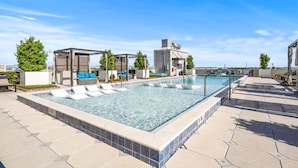A rooftop pool with lounge chairs, a water slide, and a covered seating area.