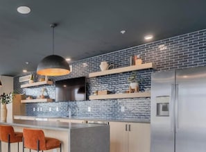 A modern kitchen with a brick backsplash, stainless steel appliances, and a pendant light.