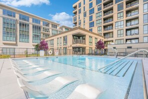 A swimming pool with a clear water surface, surrounded by a poolside area with lounge chairs.