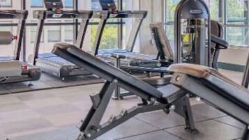 A gym with treadmills, weight machines, and a rack of dumbbells.