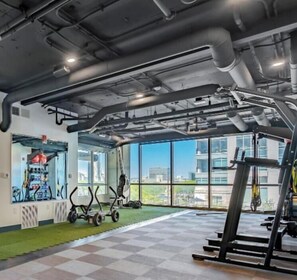 A gym with exercise equipment, large windows, and a view of buildings.