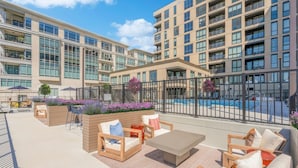 A modern hotel with a rooftop pool area, outdoor seating, and a view of the building's exterior.