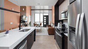Une cuisine moderne dotée d’un grand îlot central, d’appareils électroménagers en acier inoxydable et d’un coin repas avec un canapé et des chaises.