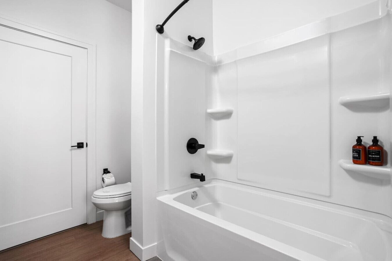 A modern bathroom with a white bathtub, a toilet, and a shower area.