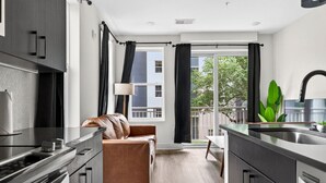 A modern kitchen with a dining area, a sofa, and a view of the outside. - Upscale 2BR Stay | Minutes from Convention Center (Tampa)