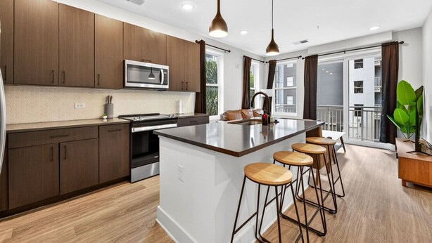 A modern kitchen with a central island, bar stools, and a view of the city. - Upscale 2BR Stay | Minutes from Convention Center (Tampa)