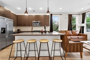 Uma cozinha moderna com uma ilha central, banquetas, um sofá e uma janela grande.