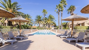 A pool area with lounge chairs and thatched umbrellas, surrounded by palm trees and a clear sky. - Holiday Home 'La Capelle 4 Persons 880' with Shared Pool, Wi-Fi and Air Conditioning (Roquefort-des-Corbières)