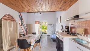 A compact kitchen with a wooden ceiling, a dining area with a table and chairs, and a view through a glass door. - Holiday Home 'La Capelle 4 Persons 880' with Shared Pool, Wi-Fi and Air Conditioning (Roquefort-des-Corbières)