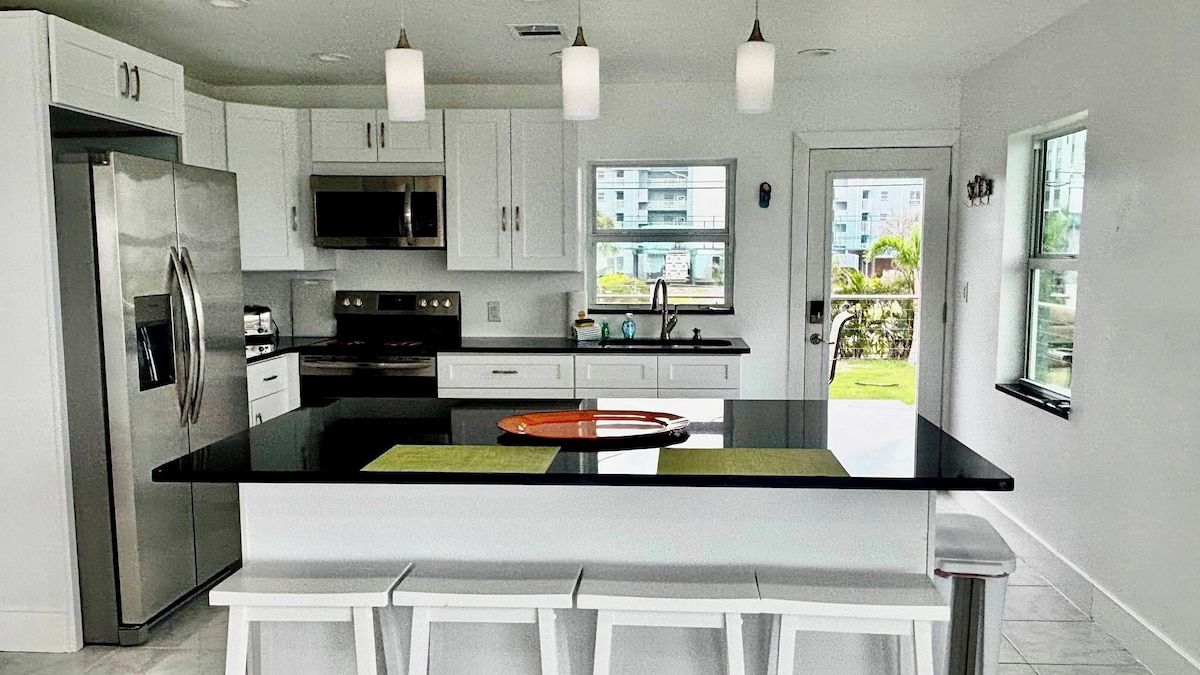 A modern kitchen with a central island, stainless steel appliances, and pendant lighting.