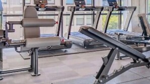 A gym with weight racks filled with dumbbells and a bench. - A+ Spacious Luxury 2BR | Pool+Lounge+Parking (Indianapolis)