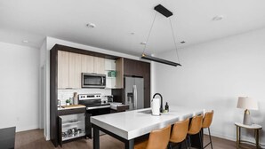 A modern kitchen with a central island, built-in appliances, and a dining area with bar stools. - A+ Spacious Luxury 2BR | Pool+Lounge+Parking (Indianapolis)
