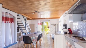 Een keuken met een eethoek, houten plafond, betegelde vloer en een trap.
