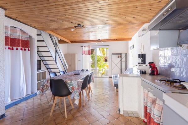 A kitchen with a dining area, wooden ceiling, tiled floor, and a staircase.
