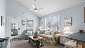 A cozy living room with a sofa, a coffee table, and a ceiling fan.