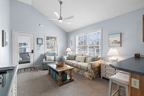 A cozy living room with a sofa, a coffee table, and a ceiling fan.