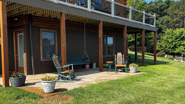 A wooden cabin with a covered porch, outdoor seating, and potted plants.