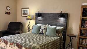 A bedroom with a bed, a chair, a lamp, a bookshelf, and a clock on the wall.