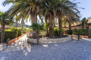 A landscaped area with palm trees, a gravel path, and a stone wall.