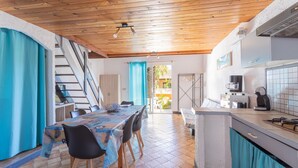 A dining area with a table, chairs, and a staircase leading to an outdoor area. - Gîte La Capelle for 7 People, with Pool (Roquefort-des-Corbières)