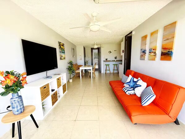 A modern living room with a sofa, TV, and a dining area.