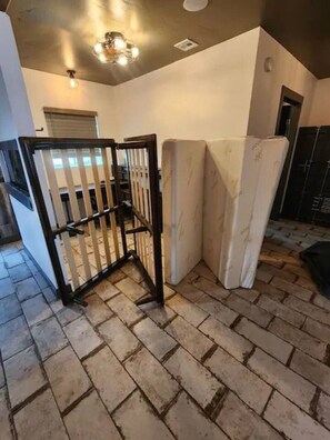 A room with a brick floor, a black metal gate, and a white wall with a small window. - The Compound in downtown (Phoenix)
