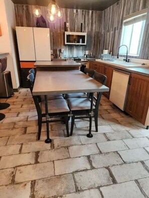 A kitchen with a central island, wooden cabinets, a microwave, and a sink. - The Compound in downtown (Phoenix)