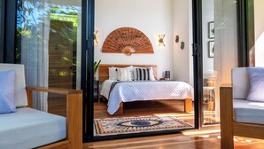 A bedroom with a bed, a wooden headboard, a wall-mounted fan, and two bedside lamps.