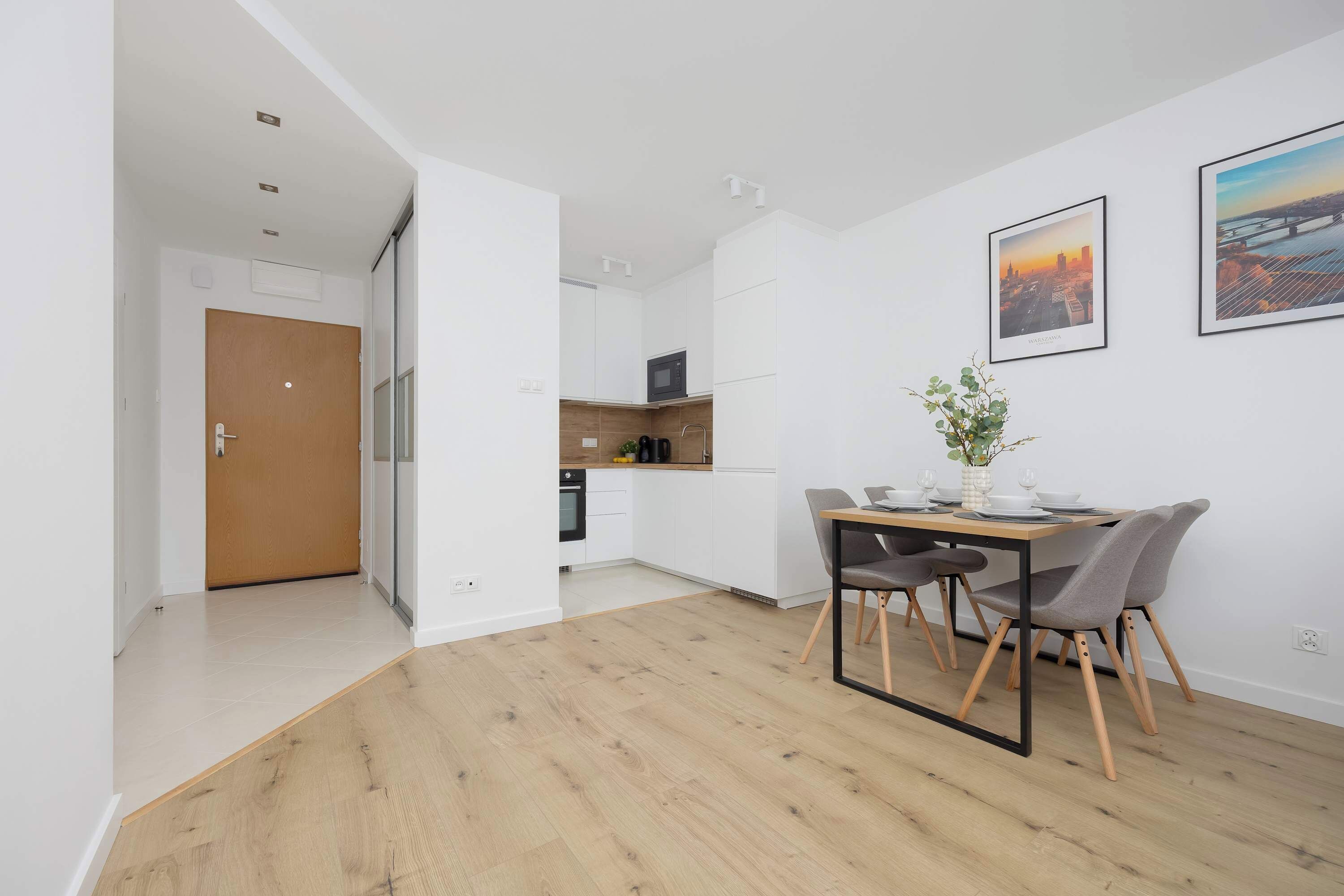 A modern kitchen with white cabinets and a dining area with a table and chairs.