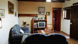 A cozy living room with a sofa, a wooden TV stand, and a wooden chair.