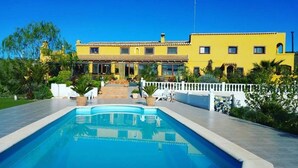 A large yellow building with a swimming pool in the foreground.