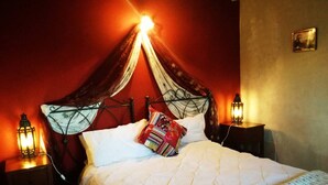 A bed with a white quilt, a red wall, and two bedside lanterns.