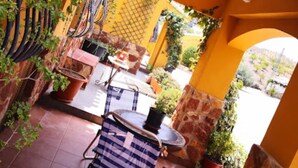 A patio with a metal chair, a table, and potted plants.