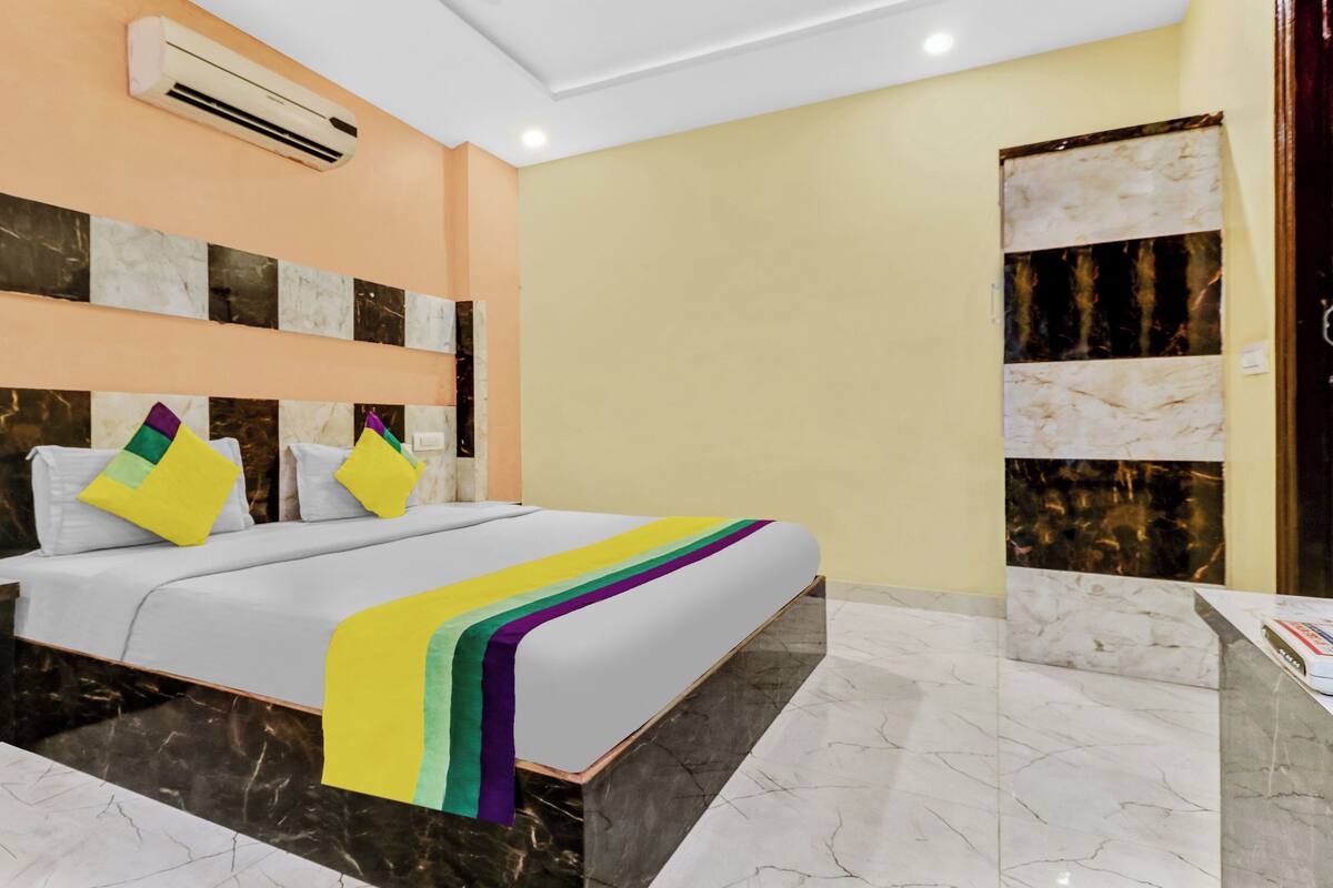 Een hotelkamer met een groot bed, marmeren vloeren, een airconditioning en een marmeren wand met een decoratief paneel.
