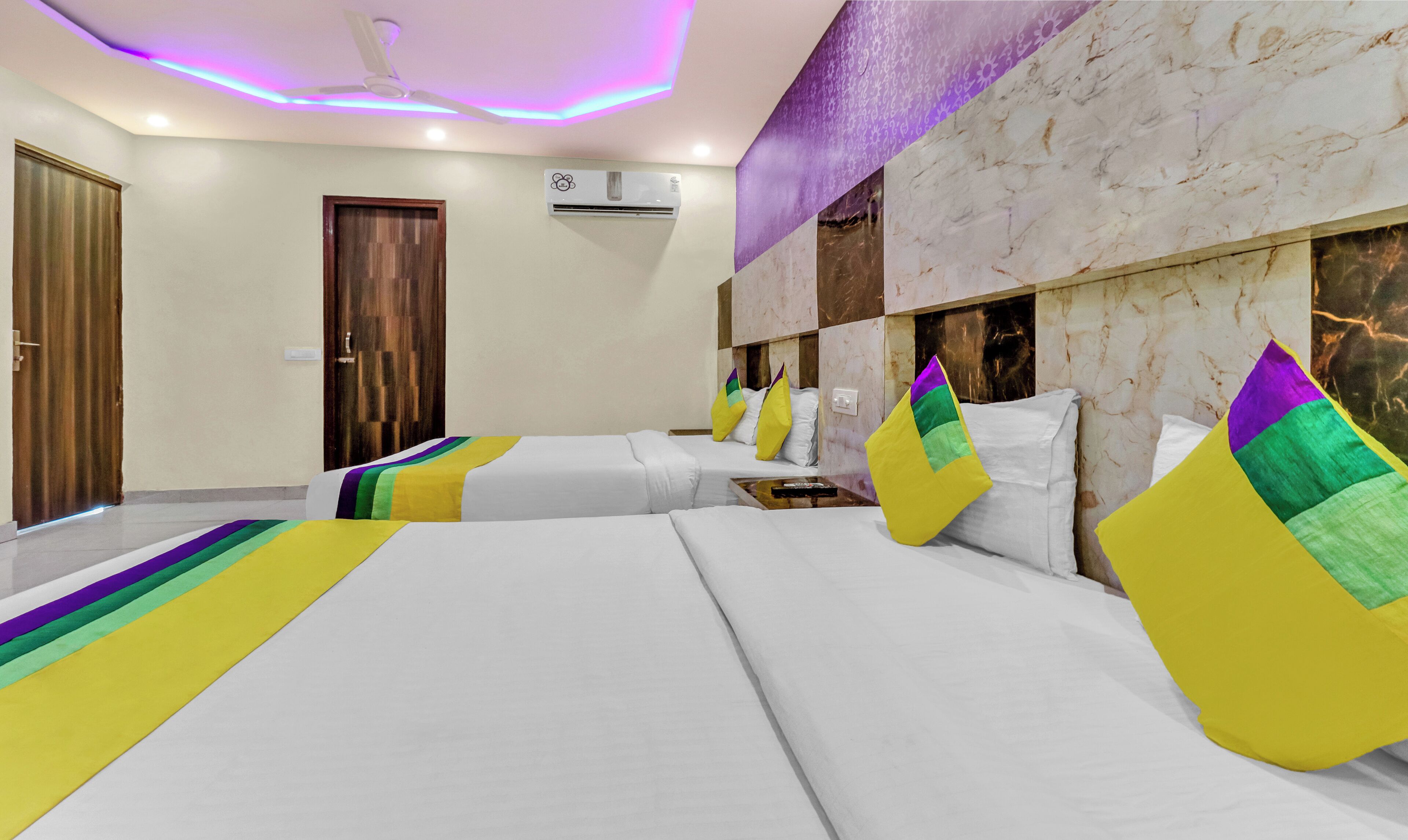 Quarto de hotel com duas camas, um ventilador de teto, um aparelho de ar condicionado e parede com padrão marmorizado.