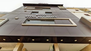 L’extérieur de l’hôtel Royal Residency présente un design moderne, avec une enseigne bien visible, de grandes fenêtres et un toit plat.