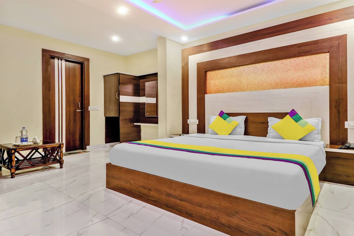 Een hotelkamer met een groot bed, een houten hoofdbord en een klein nachtkastje.